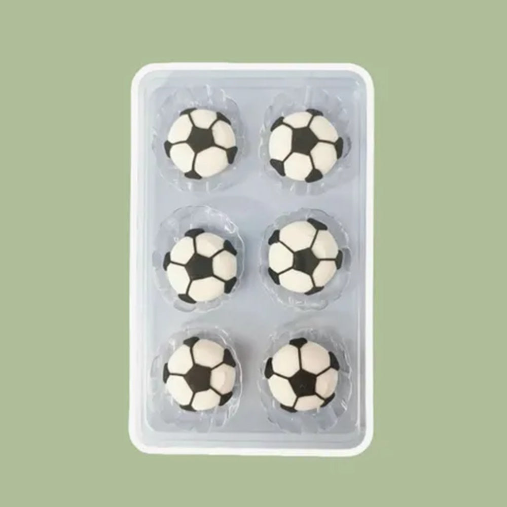 Six soccer ball-shaped royal icing cake decorations in a clear plastic packaging on a green background