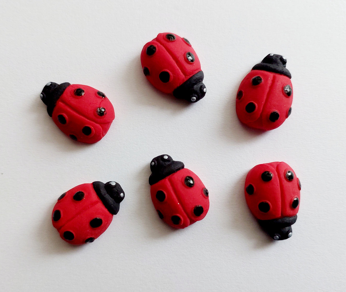 Six fondant icing ladybird decorations in red and black, intended for use as cupcake or cake toppers. Made by Cake Candy NZ