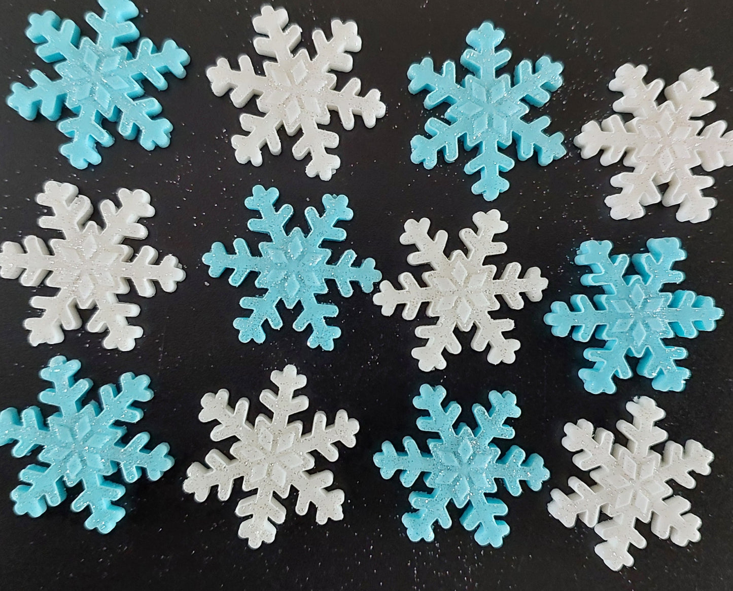 A collection of fondant icing snowflakes in blue and white colors, decorated with a sparkle.