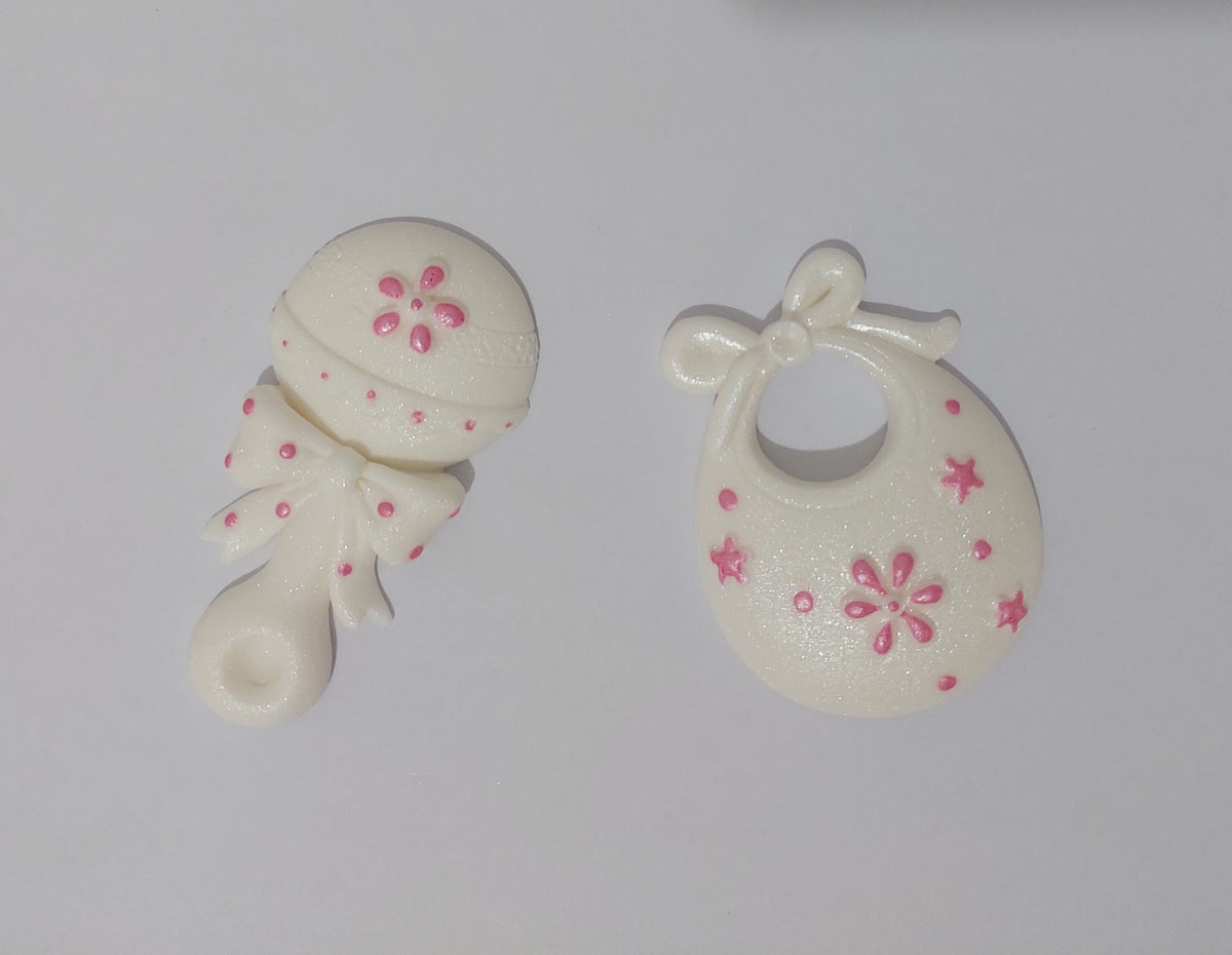Baby rattle and bib in white and pink. Edible fondant icing cake decorations