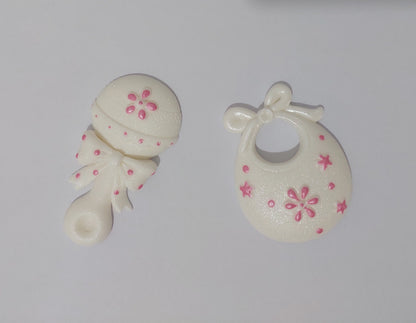 Baby rattle and bib in white and pink. Edible fondant icing cake decorations