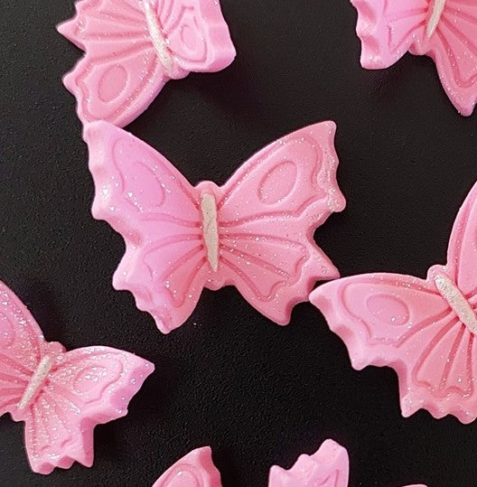 Pink butterfly-shaped candies on a black background