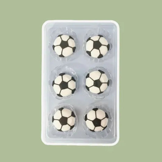 Six soccer ball-shaped royal icing cake decorations in a clear plastic packaging on a green background