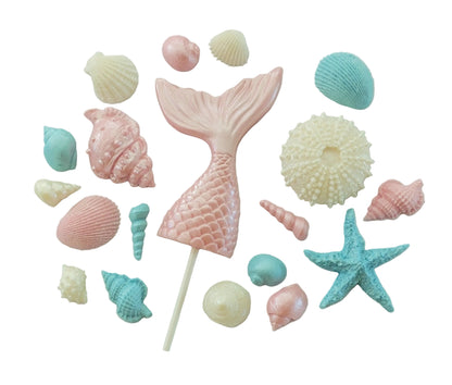 Pastel-colored pink mermaid tail cake topper surrounded by seashells and a starfish. Edible chocolate decorations by Cake Candy NZ