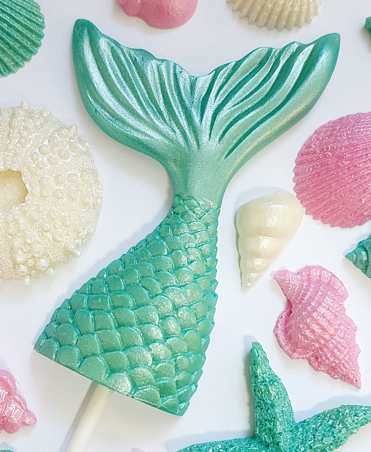 Chocolate mermaid tail, shells and starfish in aqua green, pink and cream colours. Edible cake decorations