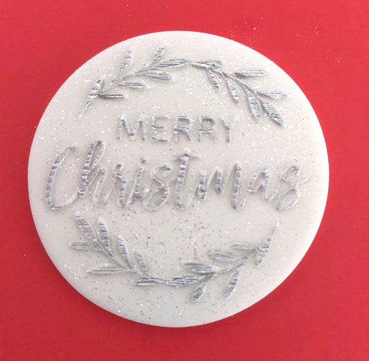 White and silver Merry Christmas fondant icing decoration on a red background.
