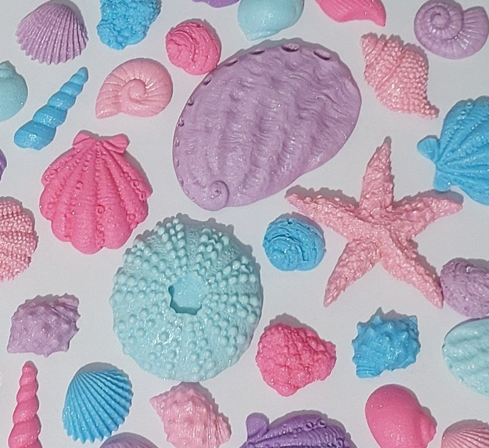 Assorted edible fondant shells in blues, purples, and pinks, with a shimmer finish. Made by Cake Candy NZ