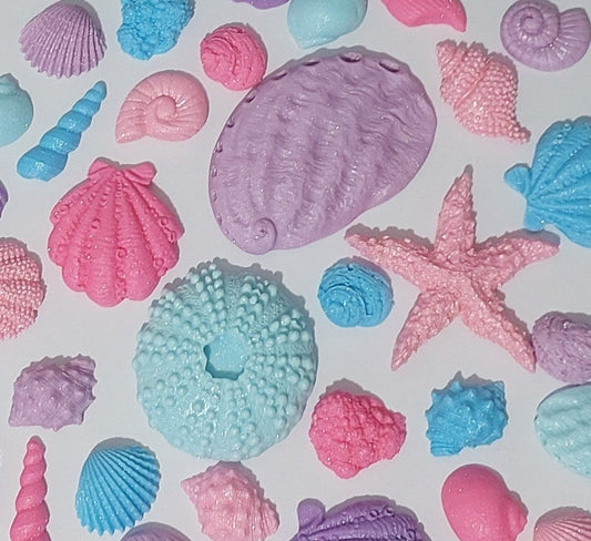 Assorted edible fondant shells in blues, purples, and pinks, with a shimmer finish. Made by Cake Candy NZ