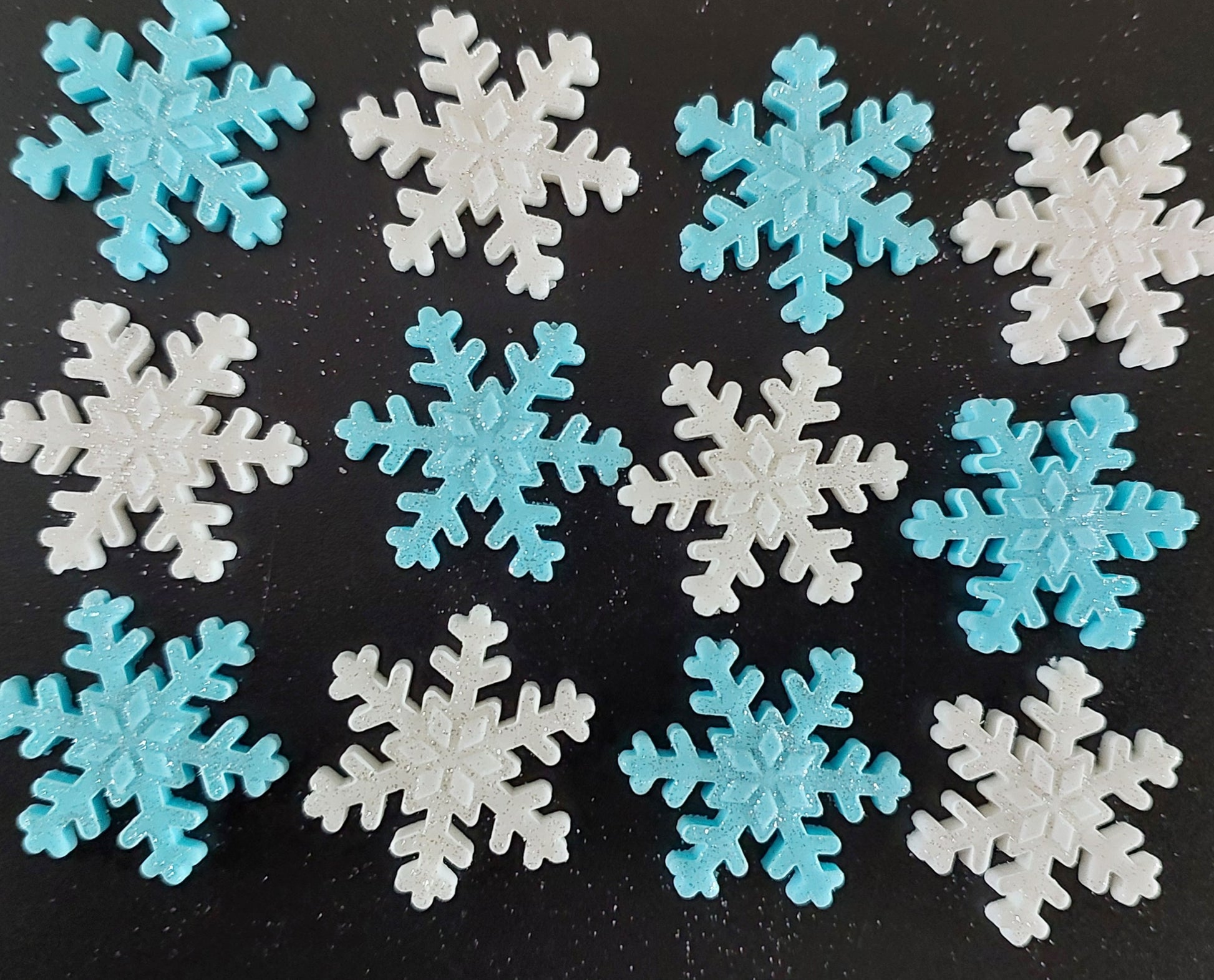 A collection of fondant icing snowflakes in blue and white colors, decorated with a sparkle.