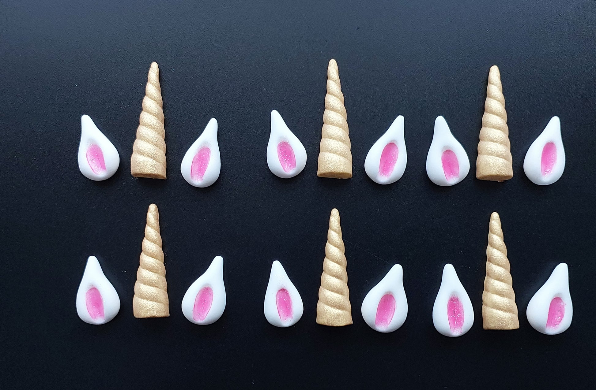 Unicorn horns and ears on a black background, edible fondant icing decorations by Cake Candy NZ